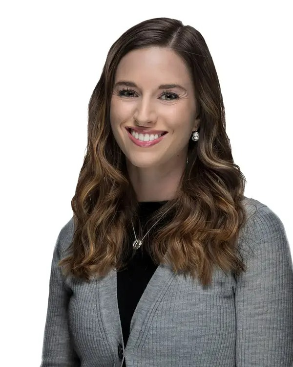 A woman with long hair and wearing a gray jacket.