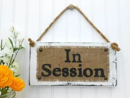 A sign hanging on the wall that says in session.